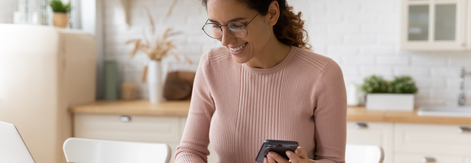 Woman in a kitchen holding a smartphone