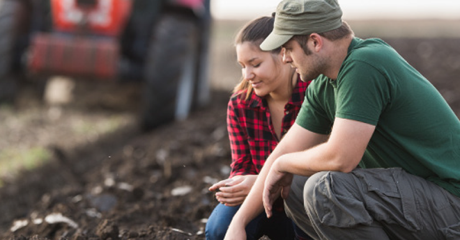 Young couple inspecting the soil on their farm